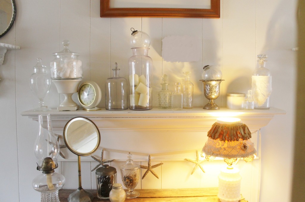 Vintage lamp, a variety of jars used in a number of ways, old bathroom mirror agains a crisp white back drop make for a lovely vignette.