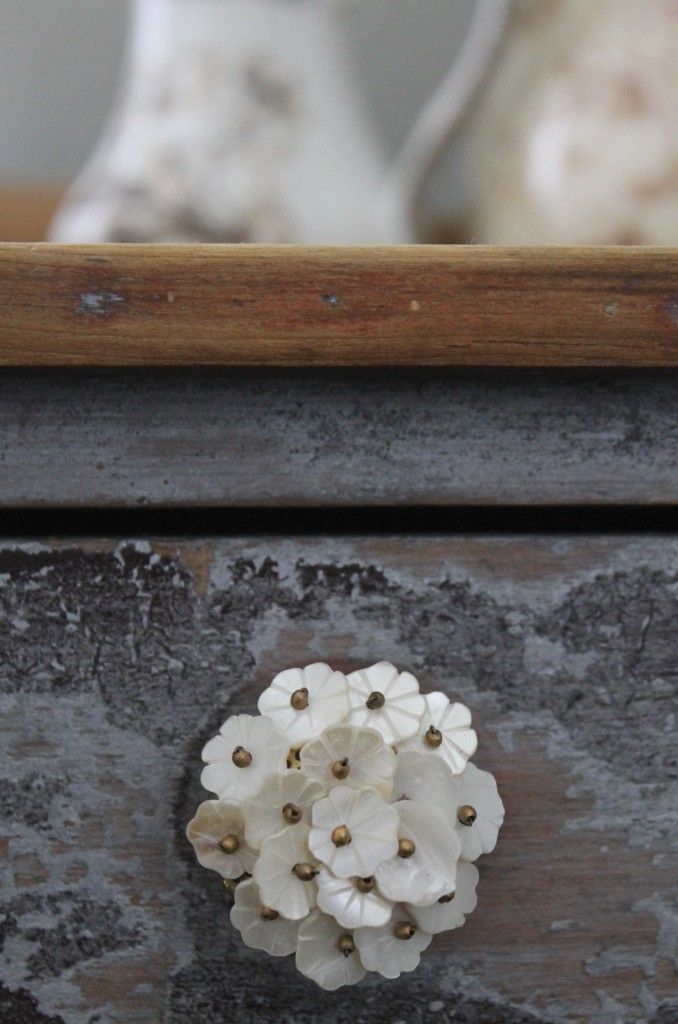The rustic against the refined; beautiful inexpensive drawer pulls add to the charm of an old, antique table.