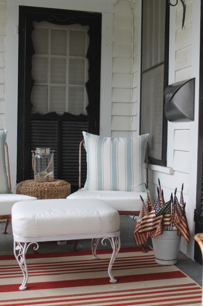 Big blue striped pillows, a lantern filled with sand, shells and citronella and an antique pewter mailbox all feel very coastal.