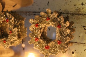 Glittery little wreath ornaments on an old, mottled mirror.